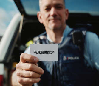 apply now image of police officer holding out a business card with the words you fit the description we're looking for
